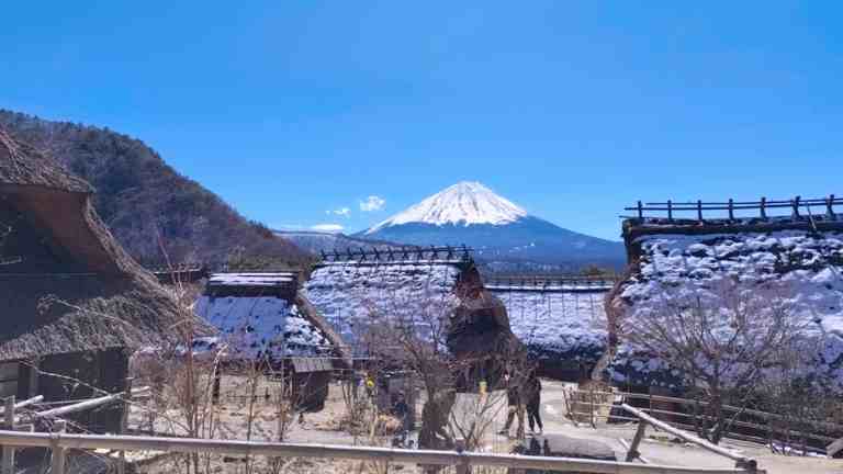 茅葺屋根の家屋の先に見える富士山の様子
